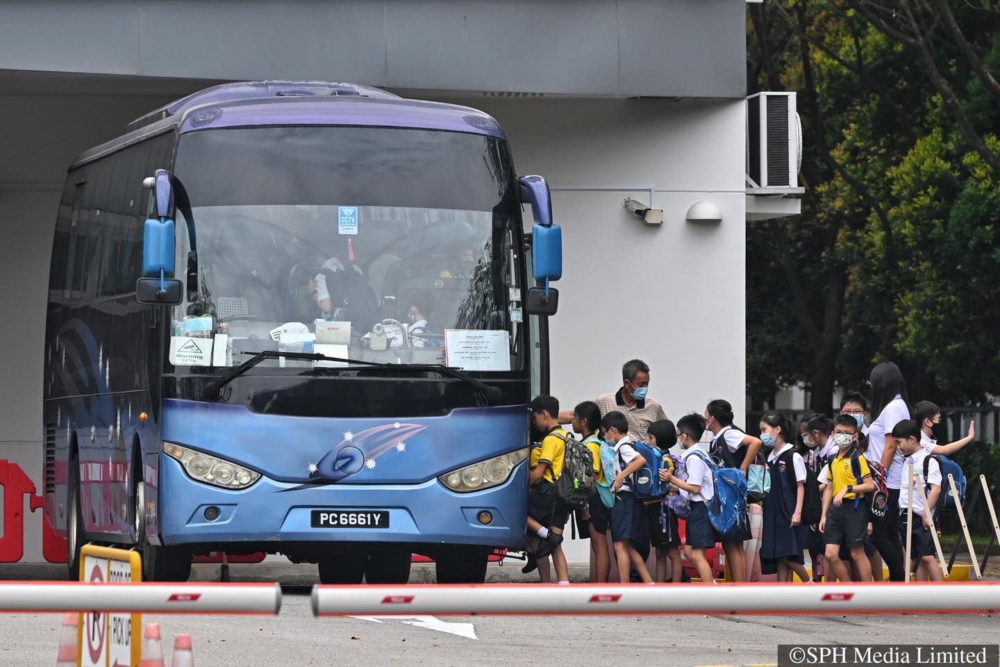 Students boarding a KAL Transport school bus with crew assistance